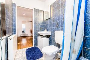 ein blau gefliestes Badezimmer mit Toilette und Waschbecken in der Unterkunft Workers Apartment am Wiener Platz in Köln