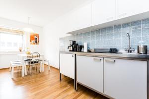 eine Küche mit weißen Schränken und einer blauen Kachelwand in der Unterkunft Workers Apartment am Wiener Platz in Köln