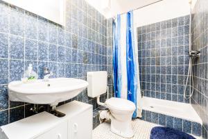 W wyłożonej niebieskimi kafelkami łazience znajduje się toaleta i umywalka. w obiekcie Workers Apartment am Wiener Platz w Kolonii