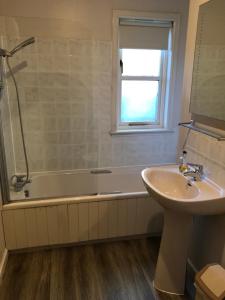 uma casa de banho com uma banheira, um lavatório e um chuveiro em Tullochwood Lodges em Forres
