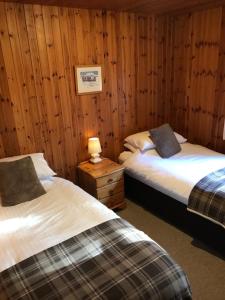 2 camas en una habitación con paredes de madera en Tullochwood Lodges, en Forres