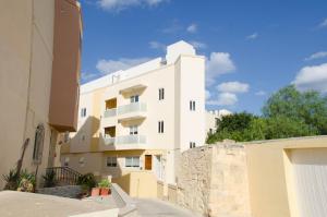 a white apartment building with a stone wall at Lorenza Letting Maisonette in Marsaxlokk