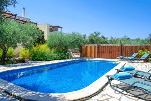 uma pequena piscina com cadeiras e uma cerca em Sentido Villas em Arménoi