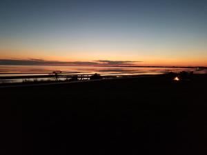 einen Sonnenuntergang am Strand mit einem Boot im Wasser in der Unterkunft Blue Spruces Cottages in Hampton 