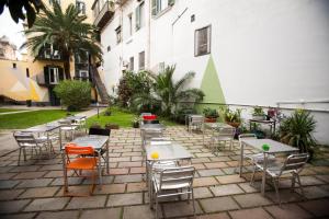 um pátio com mesas e cadeiras e um edifício em La Controra Hostel Naples em Nápoles