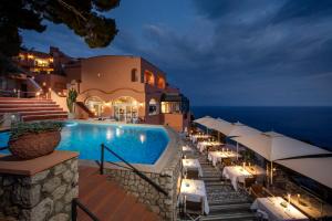 a pool with tables and umbrellas next to a building at Hotel Punta Tragara in Capri