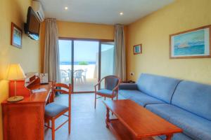a living room with a blue couch and a table at Hotel Club Sunway Punta Prima in Es Pujols