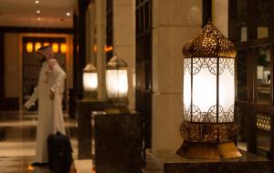a woman standing in front of a building with a lantern at Boudl Mahayel Aseer in Muhayil
