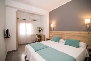 パルマ・デ・マヨルカにあるホテル アベライの大きな白いベッドと青い枕のある寝室