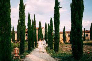 een bruid en bruidegom die over een pad lopen door een rij bomen bij Relais Ciavatta Country Hotel in Montemerano