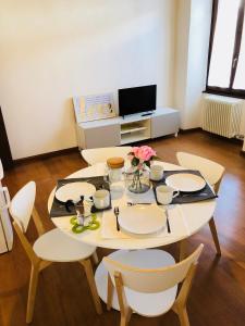 a table with chairs and a tv in a living room at Al Belenzani Appartamento in Trento