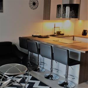 a kitchen with a counter and a bar with chairs at Apartament New York Różana 19 in Poznań