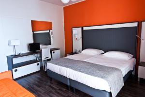 1 dormitorio con 1 cama grande y pared de color naranja en Hotel Gasparina, en Castelnuovo del Garda