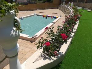 uma piscina com flores vermelhas num jardim em Villa Contessina em Cossignano