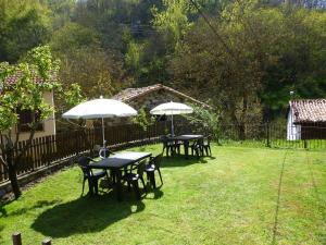 3 Tische und Stühle mit Sonnenschirmen im Hof in der Unterkunft Albergue Turístico Briz in Espinama