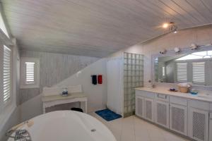 a bathroom with a tub and a sink and a mirror at Tantalus in Bridgetown +44 photos