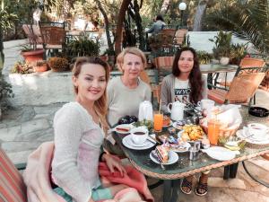a group of three women sitting at a table with food at The Delfini Hotel in Agia Marina Aegina