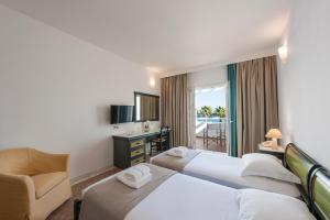 a hotel room with two beds and a chair at Saint George Hotel in Chrissi Akti