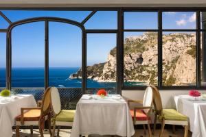 a restaurant with tables and chairs with a view of the ocean at Hotel Punta Tragara in Capri