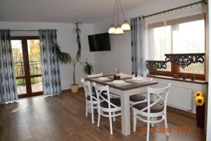 a dining room with a white table and chairs at Chatka u Stanka z bilardem , sauną i jacuzzi in Biały Dunajec