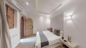 a white bedroom with a bed and a wooden door at Riad Lamzia in Marrakesh