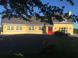 a dog standing in front of a yellow house at Curraghchase Cottage in Kilcornan