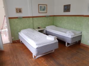 Habitación con 2 camas, paredes verdes y suelo de madera. en Röda Stallet Bed & Breakfast, en Hjo