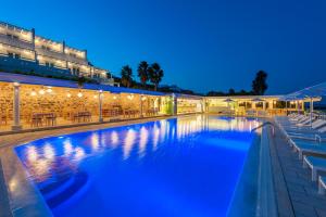 a swimming pool at night with tables and umbrellas at Saint George Hotel in Chrissi Akti