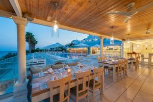 a restaurant with a pool and tables and chairs at Saint George Hotel in Chrissi Akti