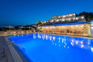 a swimming pool in front of a building at night at Saint George Hotel in Chrissi Akti