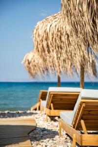 two lounge chairs and an umbrella on the beach at Erato by Samian Mare in Karlovasi