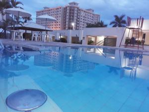 a swimming pool with chairs and a building at Eldorado Flat Service in Caldas Novas