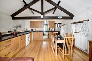 a kitchen with wooden cabinets and a table with chairs at Sunflowers Barn in Looe