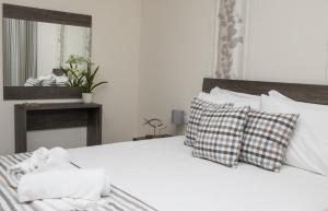 1 dormitorio con cama blanca con almohadas y espejo en Gmare, en Gerakini