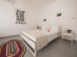 a white bedroom with a bed and a rug at Kibanda Lodge and Beach Club in Nungwi