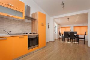 a kitchen with orange cabinets and a table with chairs at Large specious apartment in Pula