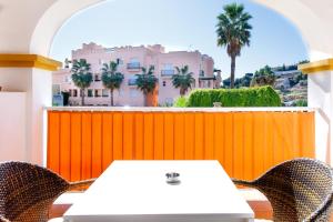 a white table and chairs on a balcony with an orange fence at AT Almoraide Rooms Suites in Nerja