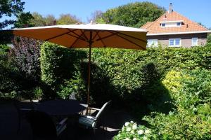einen Tisch und Stühle unter einem Regenschirm im Hof in der Unterkunft B&B Bosrand in Groesbeek