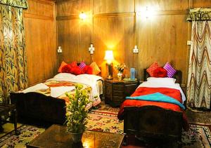 a bedroom with two beds and a table with a lamp at Chicago Group of Houseboats in Srinagar