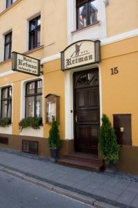 a yellow building with a brown door on a street at Hotel Retman in Toruń