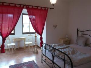 1 dormitorio con 1 cama con cortinas rojas y mesa en Kutny Residence -Chateau Schaal, en Hegyhátsál