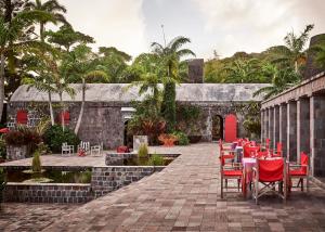 patio z czerwonymi stołami i krzesłami oraz fontanną w obiekcie Golden Rock Nevis w mieście Nevis