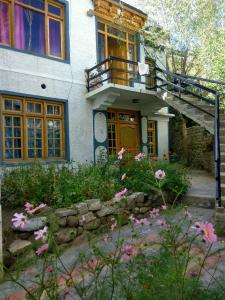 a house with a staircase and flowers in front of it at Achina in Leh