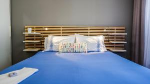 een bed met blauwe lakens en kussens in een kamer bij Cílio House - Duplex in Ponta Delgada