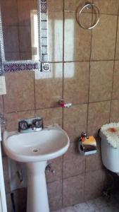 een badkamer met een witte wastafel en een spiegel bij Cabañas AURORA in Zirahuén