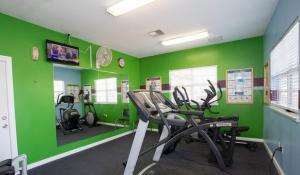 a gym with green walls and exercise bikes in a room at Tropical Palms Resort in Orlando