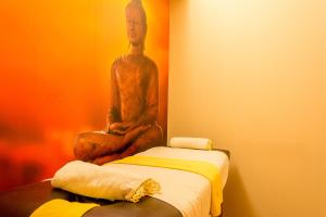 a statue of a monk sitting next to a bed at City Hotel Termal in Termas de Río Hondo