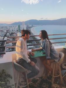 a man and a woman sitting at a table on a balcony at Da Nang Daisy Apartment in Da Nang