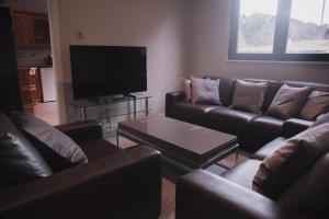 a living room with leather couches and a flat screen tv at Townhouse on the Spital in Aberdeen