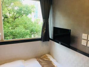 Schlafzimmer mit einem Fenster, einem Bett und einem TV in der Unterkunft Vve Vve Hotel in Hongkong